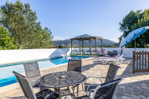 A poolside area with a pergola, lounge chairs, and a table.