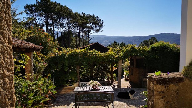 A stone patio with a bench and table, surrounded by greenery and a view of distant hills. - Rural Complex 'Shakti Rio Mino' with Lake Views, Private Pool and Wi-Fi (Eiras)