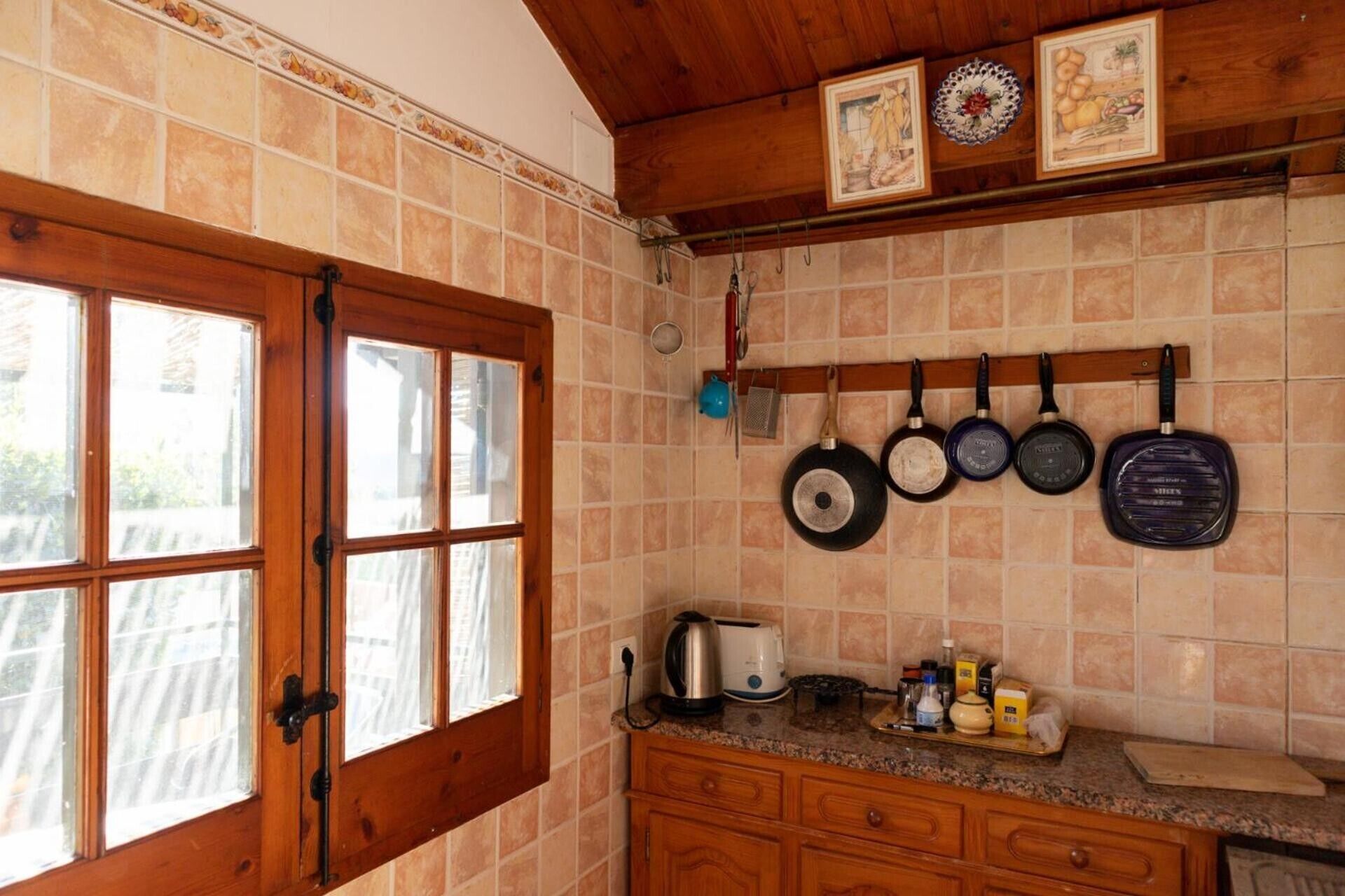 Una cocina con puerta de madera, salpicadero de azulejos y ollas colgadas.