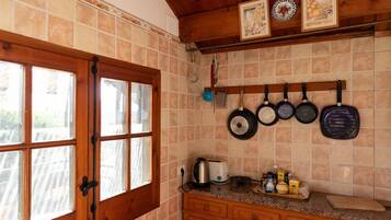 Una cocina con puerta de madera, salpicadero de azulejos y ollas colgadas.
