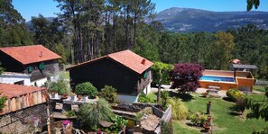 A rustic cabin with a red roof, surrounded by lush greenery and a mountain backdrop. - Rural Complex 'Shakti Rio Mino' with Lake Views, Private Pool and Wi-Fi (Eiras)