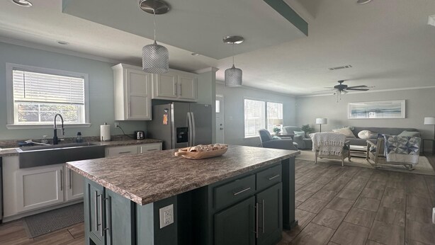 A spacious kitchen with granite countertops, a central island, and a dining area with a sofa and chairs.