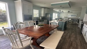 A spacious kitchen with white cabinetry, a wooden dining table, and a built-in island with seating.