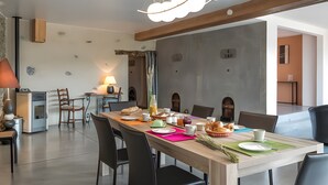 Un comedor con una larga mesa, sillas y una variedad de platos y bebidas.