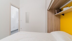 Une chambre à coucher avec un lit, une porte, un miroir et une étagère remplie de livres.