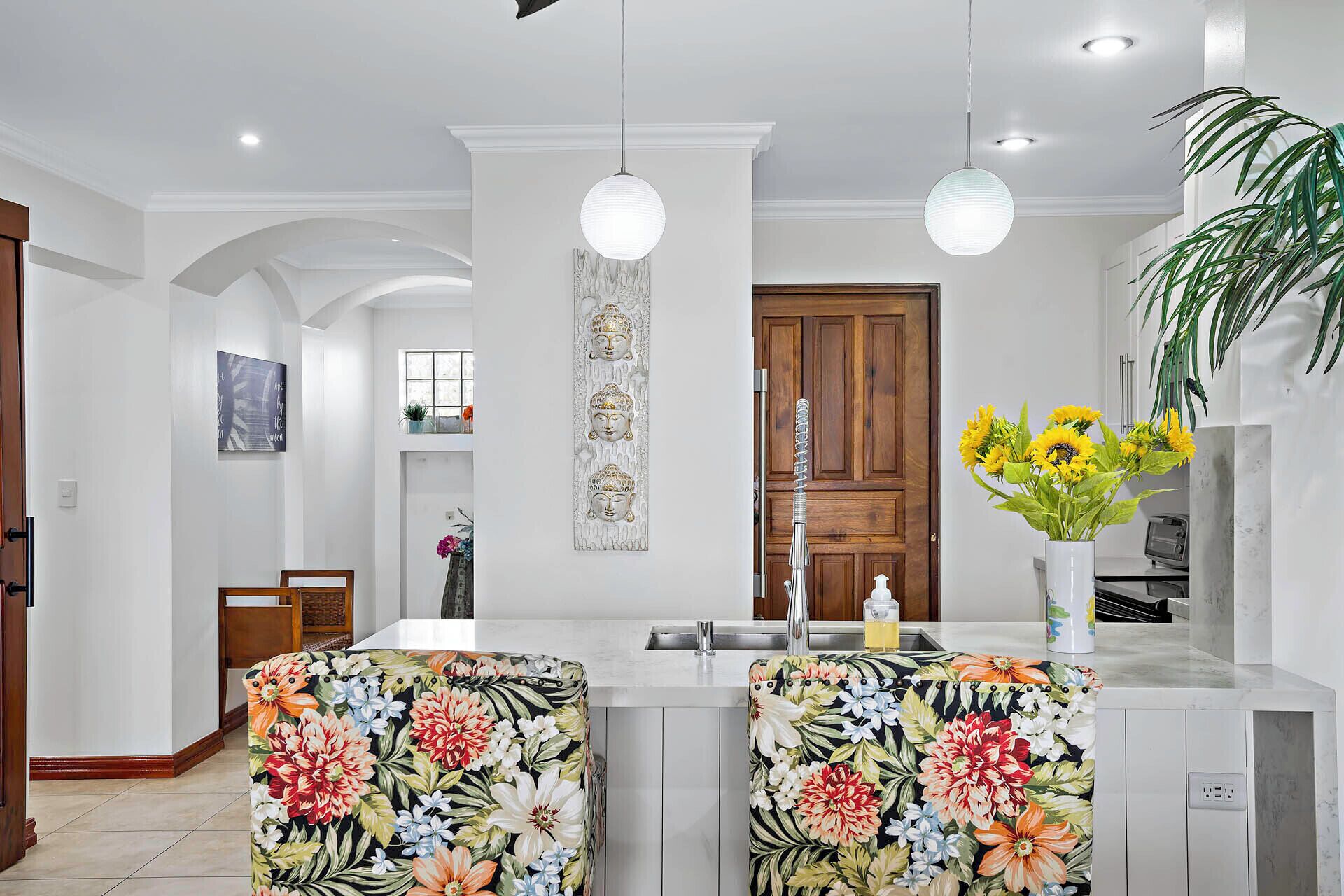 Una cocina moderna con una isla central, iluminación colgante y un elemento decorativo en la pared.