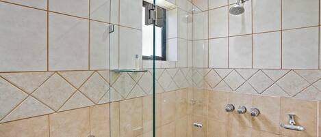 A modern bathroom with beige tiles, a glass shower enclosure, a towel rack, and a showerhead.