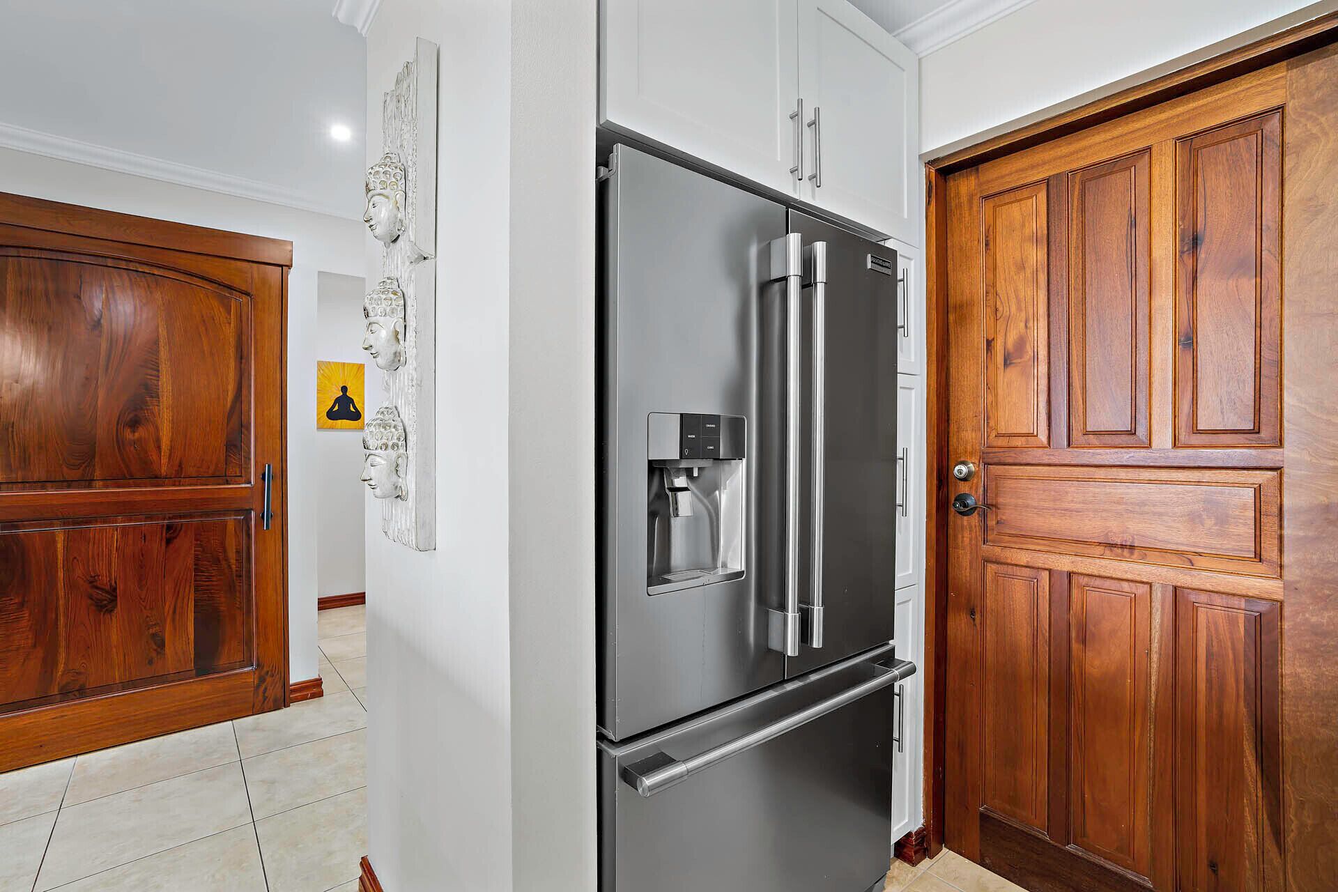 A modern kitchen with a stainless steel refrigerator, a water dispenser, and a wooden door.