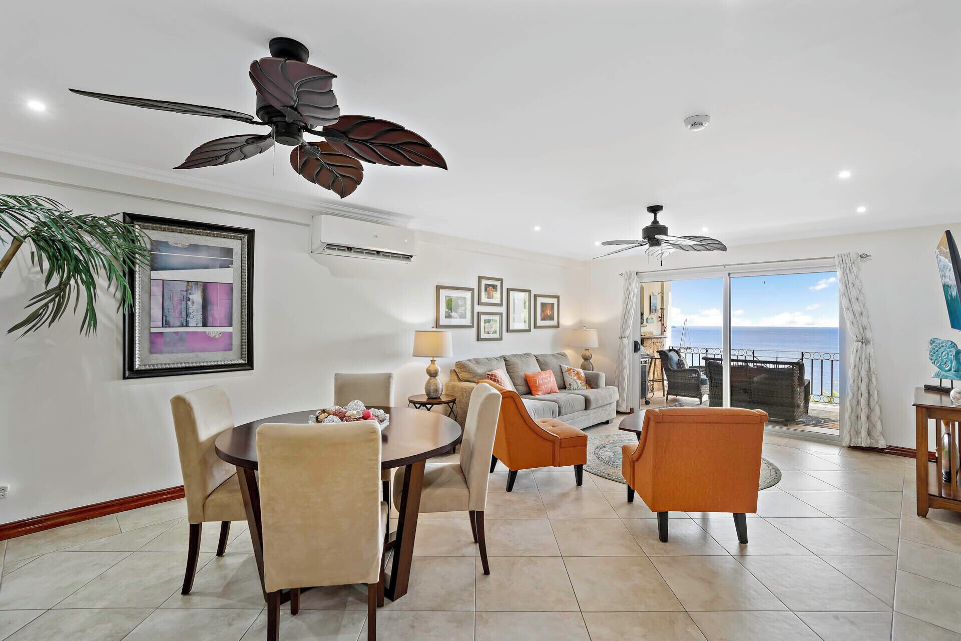 A spacious living area with a dining set, a sofa, and a ceiling fan.