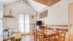 Une pièce confortable avec un canapé, une table à manger en bois, des chaises, un téléviseur et un coin cuisine.