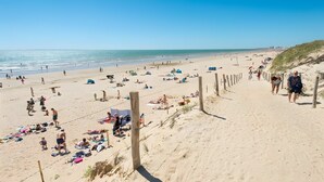 A beach with people sunbathing and walking along the shore. - 4-Star Le Bois Tordu Campsite: Mobile Home 300 Meters from La Pège Beach (Saint-Hilaire-de-Riez)