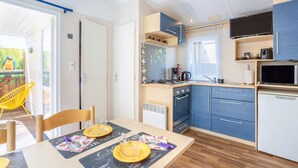 Una cocina compacta con microondas, estufa y alacenas, un comedor con mesa y sillas, y vistas al exterior.