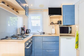 A compact kitchen with a gas stove, microwave, and sink.