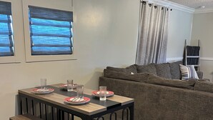 Un comedor con una mesa preparada para dos, un banco y un sofá al fondo.