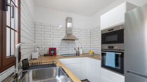 A modern kitchen with a stainless steel sink, a built-in oven, and a microwave.