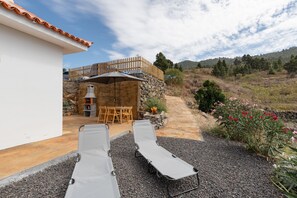 Un patio con dos sillones, una mesa y una parrilla.