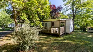 A small, single-story mobile home with a wooden deck and a fenced yard.