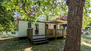 A small, single-story mobile home with a porch and steps leading to the entrance.