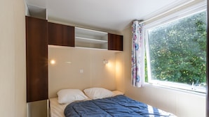 Ein Schlafzimmer mit Bett, einem fensterbepflanzten Fenster und eingebauten Regalen.