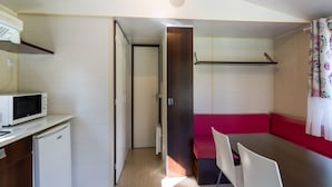 Eine kleine Küchenzeile mit Mikrowelle, Kühlschrank und einem Tisch.