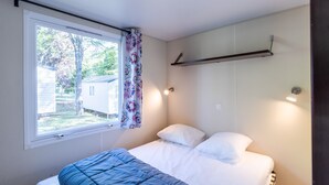Un dormitorio con cama, ventana y estante montado en la pared.