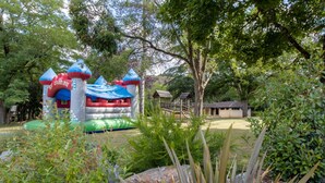 A large inflatable structure with a flag, surrounded by greenery and a small building. - Mobile Home 'Le Noyer' with Shared Pool, Private Terrace and Private Garden (Saint-Pompon)