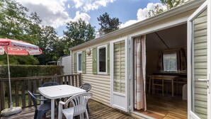 A mobile home with a deck, a table with chairs, and a covered area with a table and chairs. - Mobile Home 'Le Noyer' with Shared Pool, Private Terrace and Private Garden (Saint-Pompon)