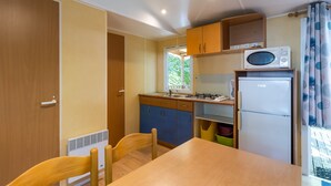 Une cuisine de taille réduite, avec une table en bois, des chaises, un four à micro-ondes, un réfrigérateur et des placards.