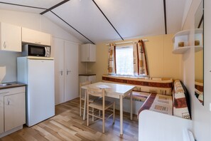 A compact kitchen with a microwave, refrigerator, and wooden table. - Mobile Home 'La Truffière' with Shared Pool, Private Terrace and Private Garden (Saint-Pompon)