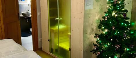 Ein Schlafzimmer mit einem Bett, einem Schrank mit Glastüren, einem Weihnachtsbaum und einem Fernseher an der Wand.
