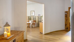 Ein Zimmer mit Holzboden, einem Tisch mit Stühlen, einem Schrank und einer beleuchteten Laterne.