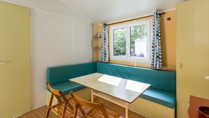 Une pièce avec un banc de couleur turquoise, une table blanche et deux chaises en bois.