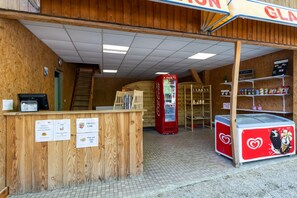 Un interior de madera con un refrigerador Coca-Cola, un congelador con diseño de corazón y una escalera que lleva a una puerta.
