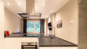 Una cocina moderna con extractor de acero inoxidable, horno empotrado y un amplio ventanal con vistas al exterior.