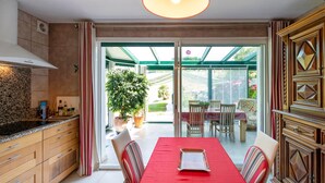 A modern kitchen with wooden cabinets, a granite countertop, and a red dining table with chairs.