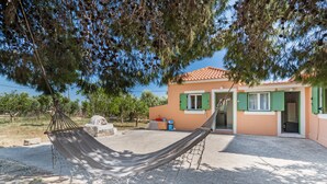 A house with a hammock in the yard, green shutters, and a tiled roof.