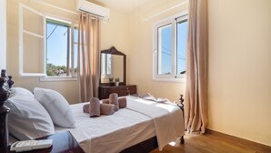 A bedroom with a bed, a dresser, a mirror, and two windows with curtains.