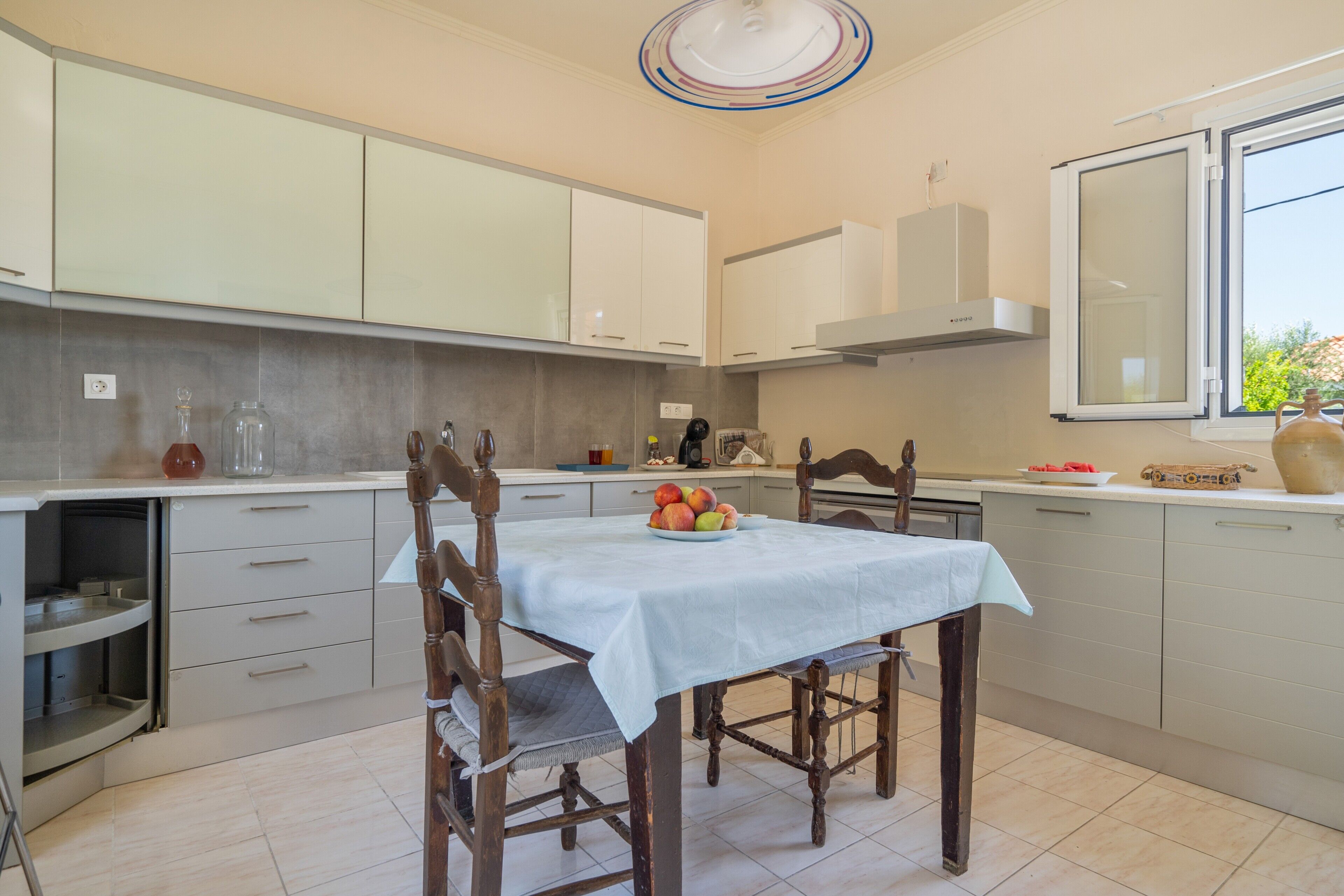 A modern kitchen with a dining table, wooden chairs, and a window with a view.
