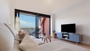 Ein modernes Wohnzimmer mit einer Couch, einem Fernseher und einem Balkon mit Blick.