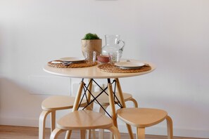 A round table with a woven placemat, two clear glasses, a small potted plant, and a pitcher.