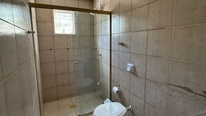 Een badkamer met een douchecabine van glas, een toilet en een wastafel.
