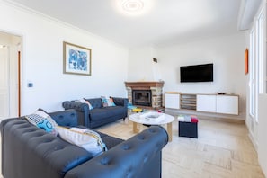 Een woonkamer met een open haard, een bank, een televisie en een kast.