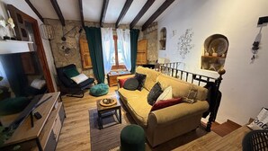 A cozy living room with a sofa, a chair, a wooden coffee table, and a small round table with a cup. - Casa Trinidad – private terrace, parking, historic center of Dénia (Dénia)