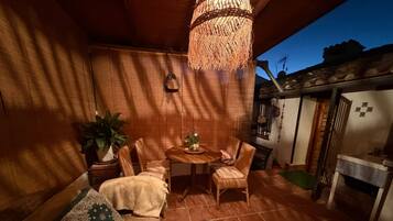 Et hyggeligt opholdsområde indendørs med sofa, stole, et lille bord og en hængende lampe.
