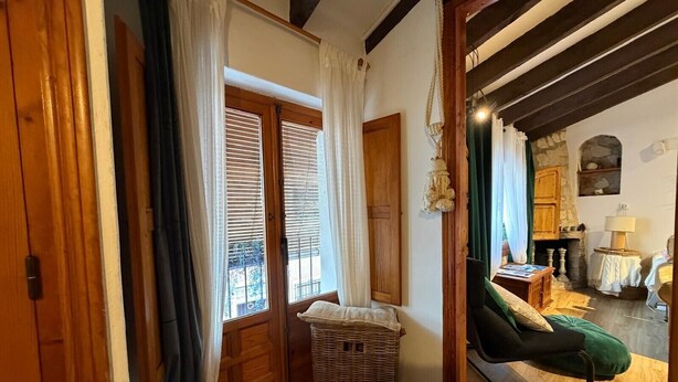 A room with a wooden floor, a green chair, a wicker basket, and a wooden door. - Casa Trinidad – private terrace, parking, historic center of Dénia (Dénia)
