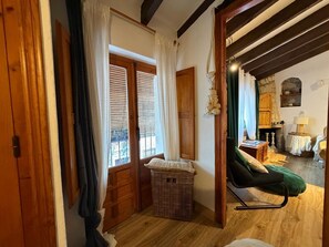 Una habitación con piso de madera, una silla verde, una cesta de mimbre y una puerta de madera.