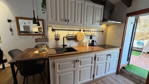 A kitchen with white cabinets, a wooden countertop, and a dining area with chairs. - Casa Trinidad – private terrace, parking, historic center of Dénia (Dénia)