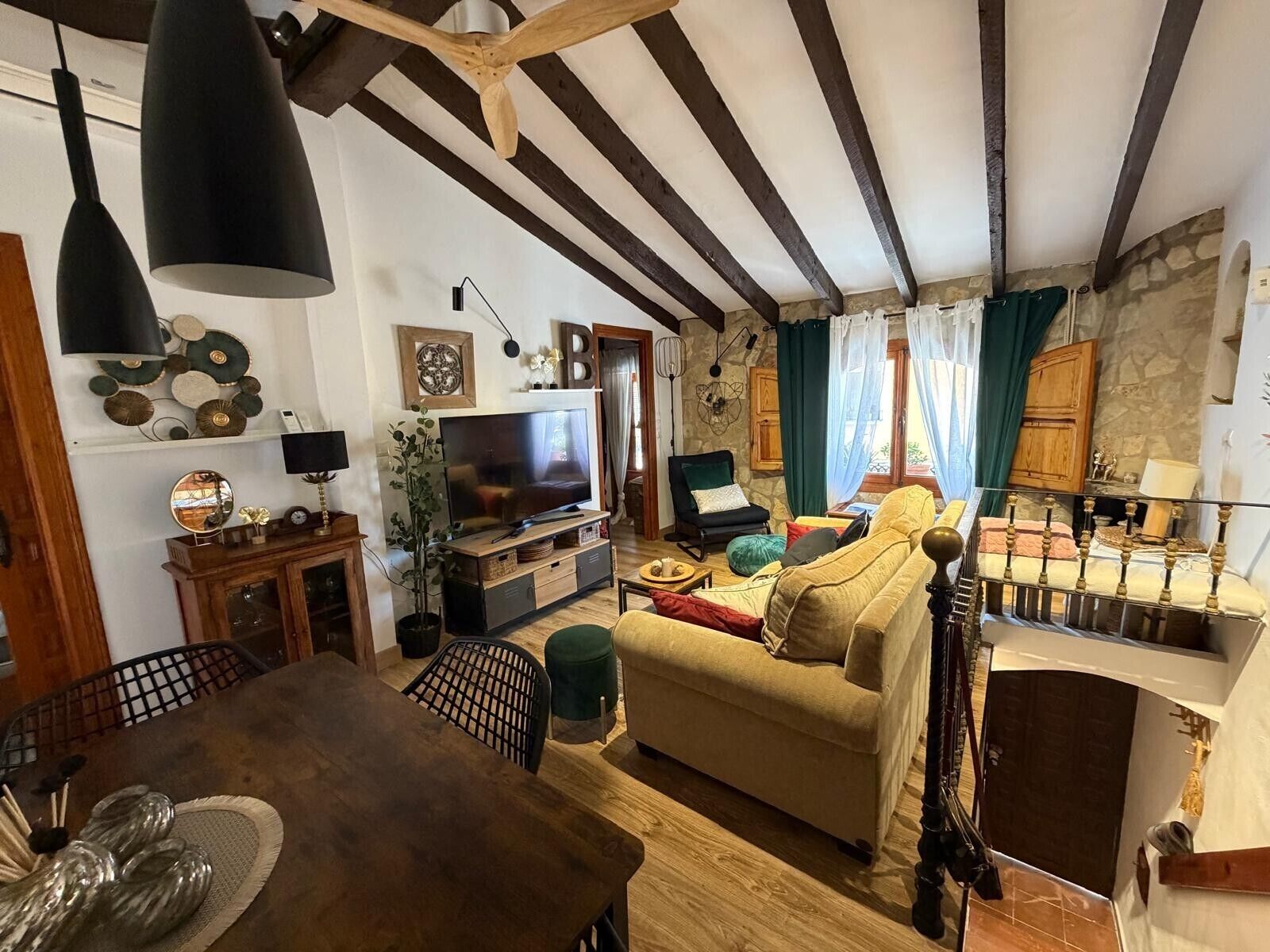 A cozy living room with a wooden dining table, sofa, and TV.