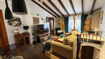 A cozy living room with a wooden dining table, sofa, and TV.