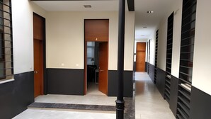 Un couloir doté d’un sol en marbre, de murs noirs et blancs et de portes donnant sur différentes pièces.